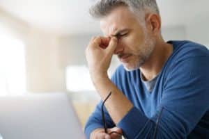 a man holds the bridge of his nose as he considers alcoholism and memory loss as well as alcohol and mental health