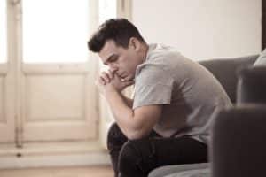 a man sits on a couch as he considers heroin withdrawal symptoms and quitting heroin addiction