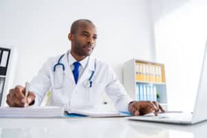 a doctor uses a computer at a desk possibly researching Heroin use in Colorado