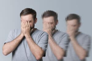 a person puts their hands on their face in three increasingly blurry portraits to show detox hallucinations and alcohol withdrawal