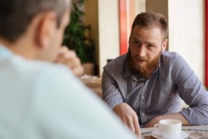 a person addresses another at a table possibly offering Help with meth addiction