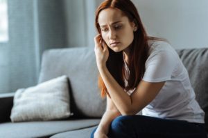 a person on a couch looks sad as they struggle with Oxycontin abuse