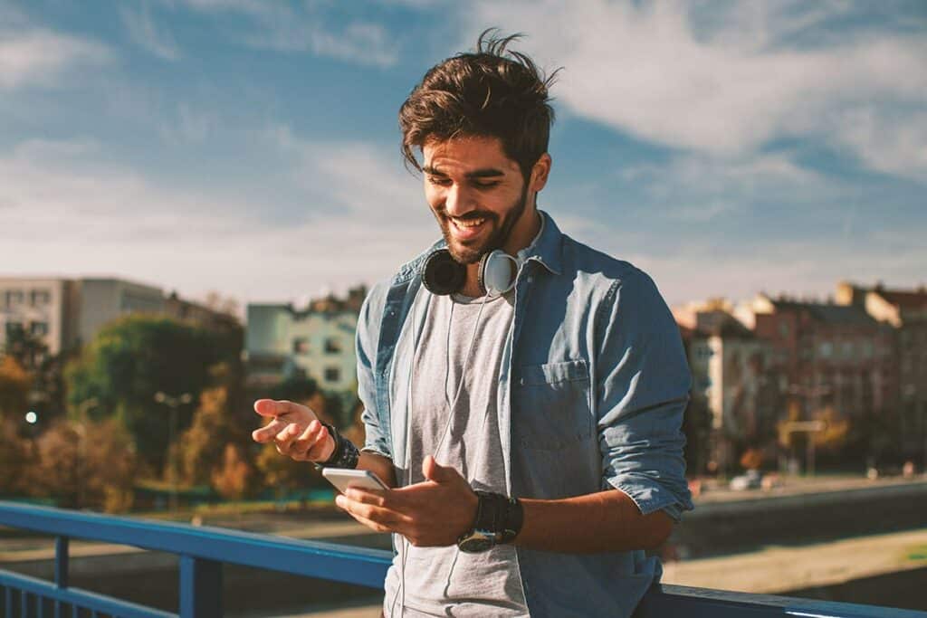 a person outside smiling while looking up on their phone the best supplements for alcohol cravings