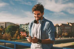 a person outside smiling while looking up on their phone the best supplements for alcohol cravings