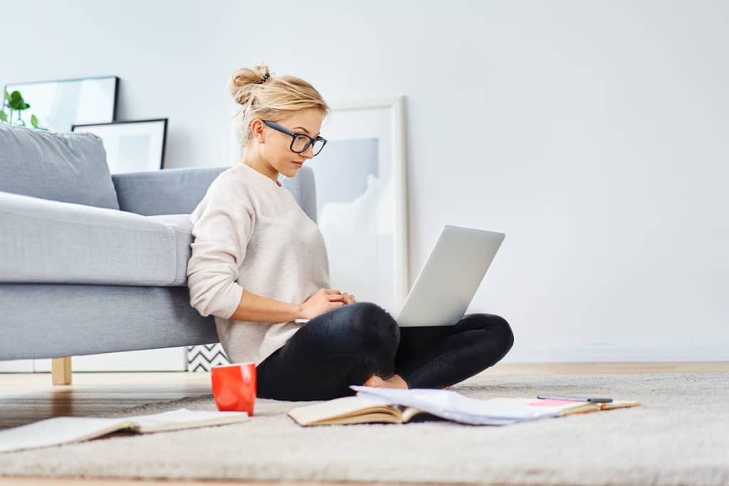 a person sits on the floor and searches for Treat alcohol withdrawal at home on a computer