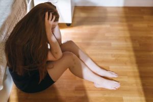 a person sitting on the floor with their head in their hands, anxious and learning about Mental health and substance abuse