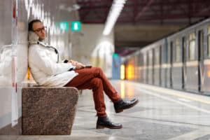 a person sits in on a bench waiting for a subway wondering about signs you're dealing with an alcoholic