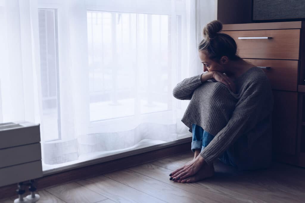 a person looks anxious by a window to show the root causes of anxiety