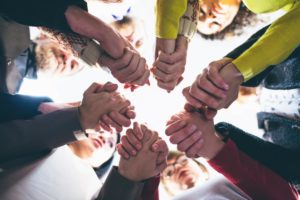 a group of people holding hands learns of the benefits of group therapy