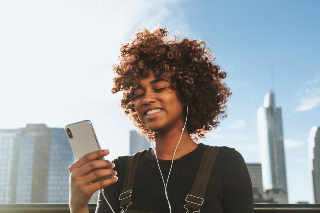 a person listening to music on their phone outside in a city learns of the benefits of music therapy