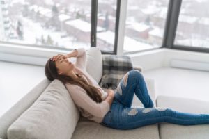 a person lays on a couch with the snowy background and overcomes seasonal depression