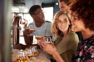 a group of people drink mead at a bar safely after learning about social drinking vs alcoholism
