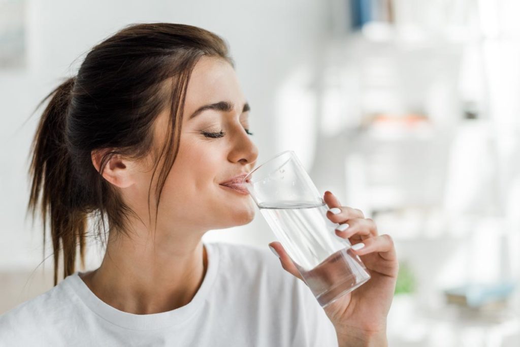 a person happily drinks water while avoiding alcohol cravings