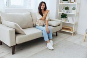 a person sits on a couch rubbing their shoulder while overcoming heroin addiction