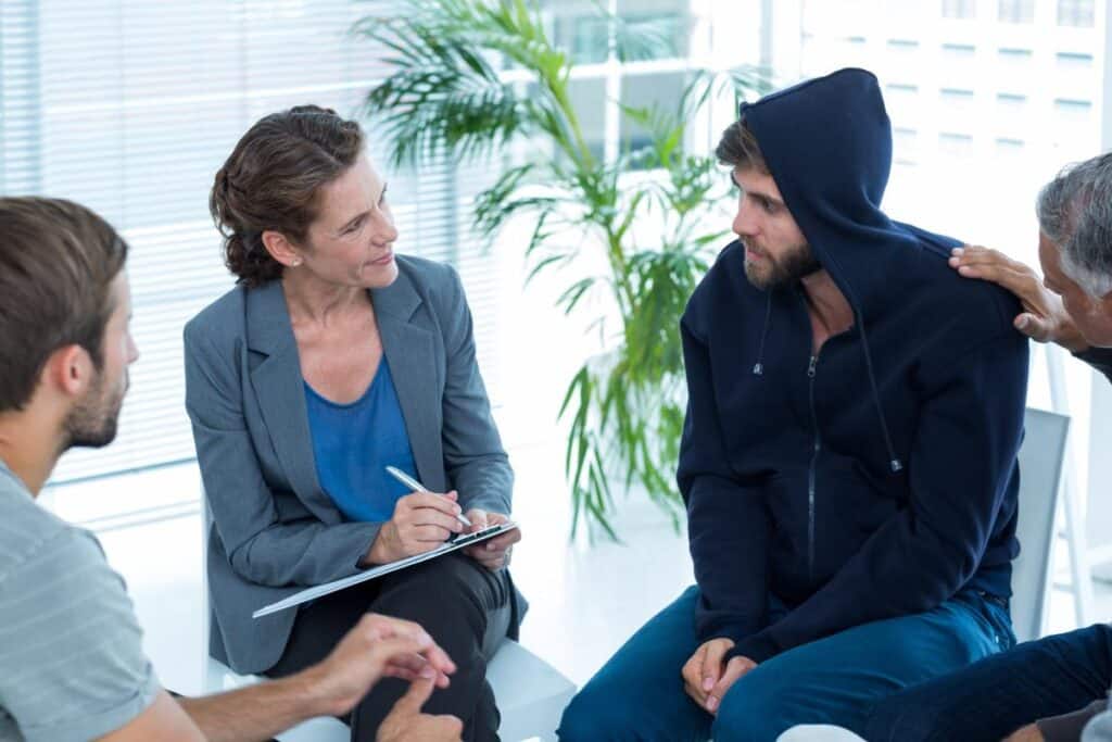 a group of people chat to a therapist about marijuana withdrawals while sitting in a circle