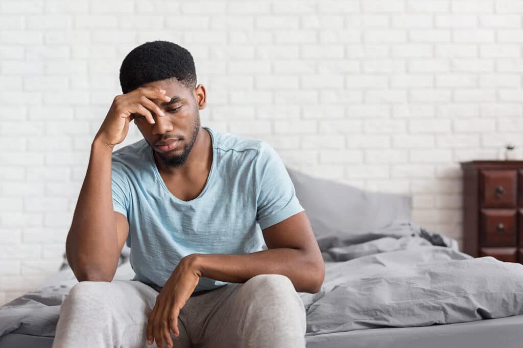 a person looks sick at the end of a bed showing signs of cocaine addiction