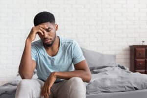 a person looks sick at the end of a bed showing signs of cocaine addiction