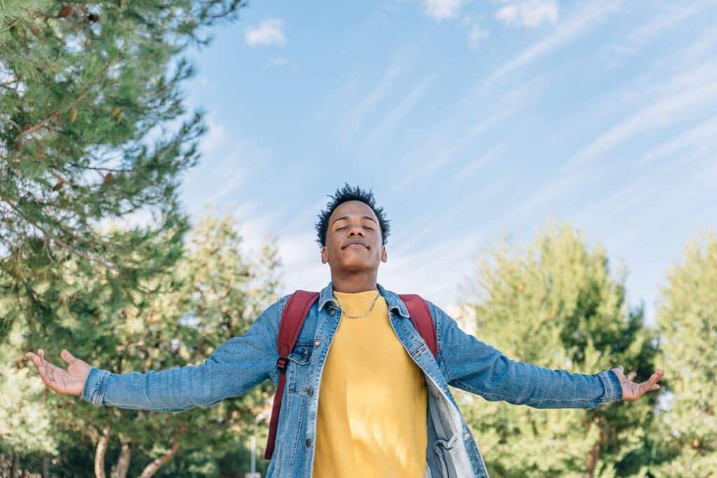 a person stands outside smiling with arms wide to show natural alternatives to xanax