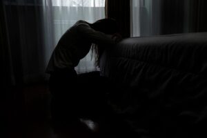 a person leans against a couch in the dark to show the long term effects of Xanax addiction