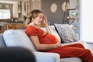 a pregnant person puts her hand on her head and contemplates heroin use while pregnant