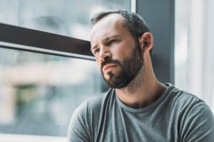 a person looks sadly out of a window and wondering about how long oxycontin in your system lasts