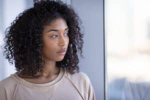 a person with curly long hair looks away from the camera while coping with addiction relapse