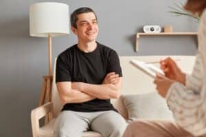 a person sits on a couch and smiles at a therapist while asking what is cognitive behavioral therapy