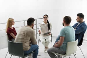 a group of people sit in a circle in chairs and talk during fentanyl treatment