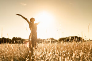 a person raises their arms wide in a sunny field to show how to prevent relapse