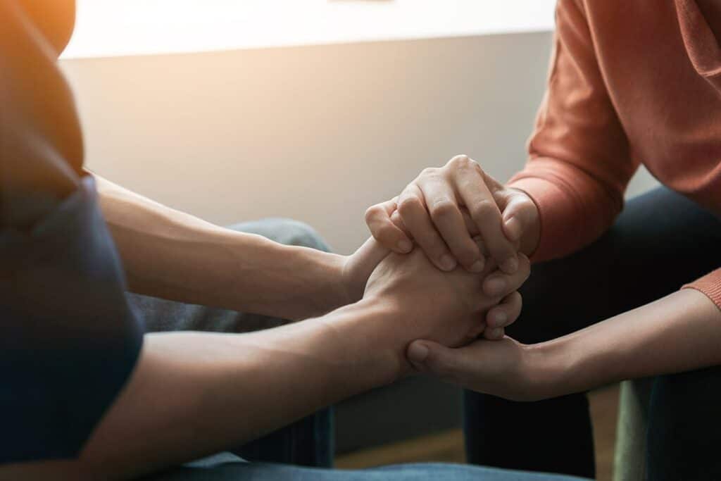 two people hold hands as they discuss signs of meth addiction