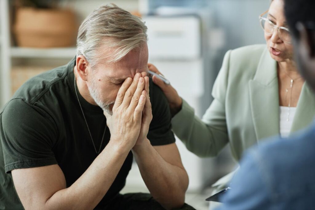 a person crying into their hands learns the importance of ptsd treatment