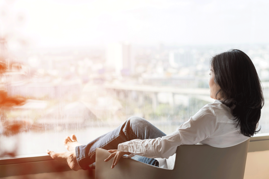 a person relaxes in a chair overlooking a city to show self-care activities to help combat anxiety