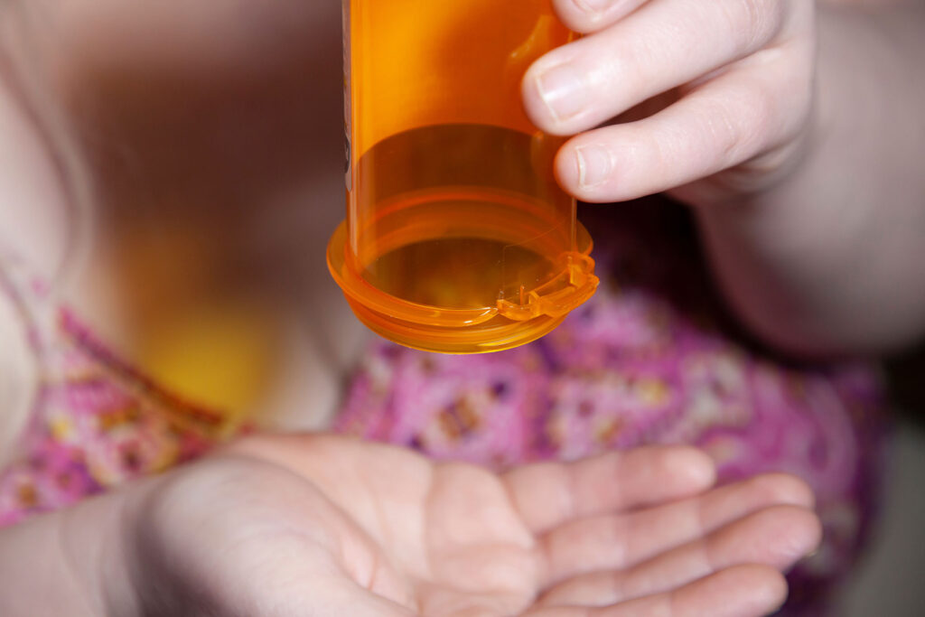a person trying to empty an empty pill bottle to show xanax addiction symptoms and signs