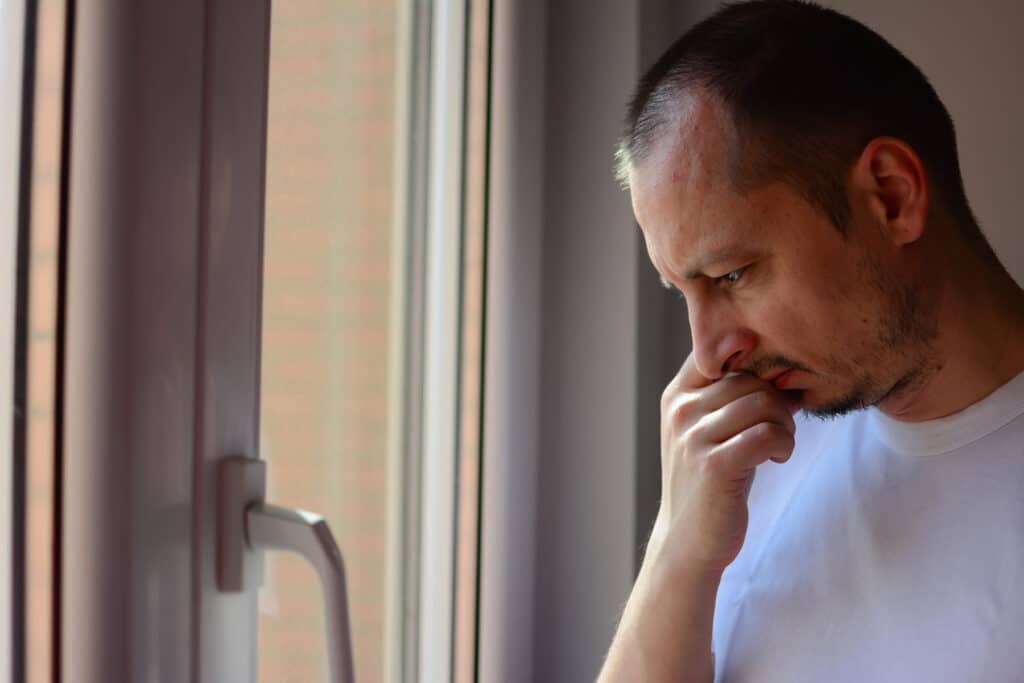 a person looks out a window after knowing a sign it's time for a drug detox